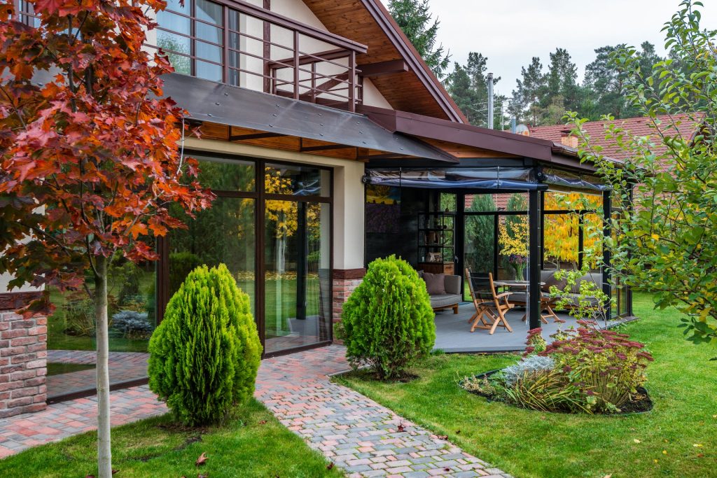 Modernes Haus mit gemütlicher Terrasse und Garten im Herbst, Gartenservice Schmidt